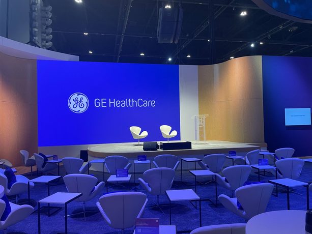 An empty general session room before doors, stage lit and chairs set in rows.