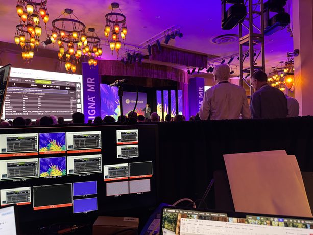A production console glowing at the back of a warm-lit gala ballroom.